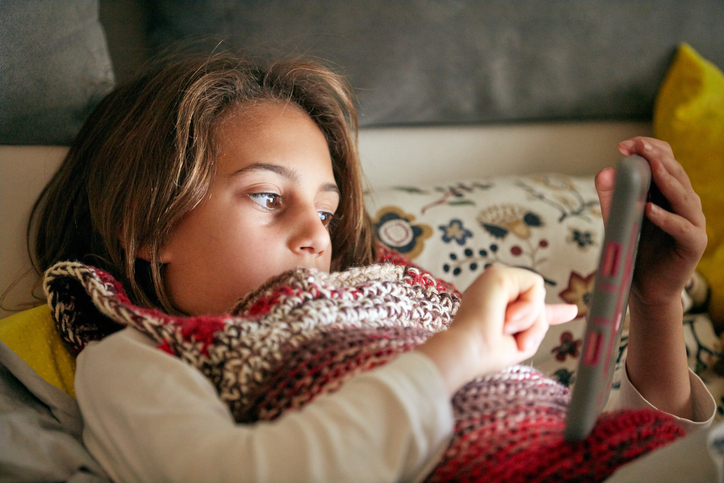 Little girl studying and doing homework at home with tablet.