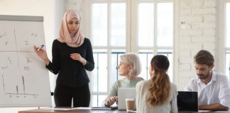 millennial female Arabic speaker explaining presentation to older and young colleagues at office.